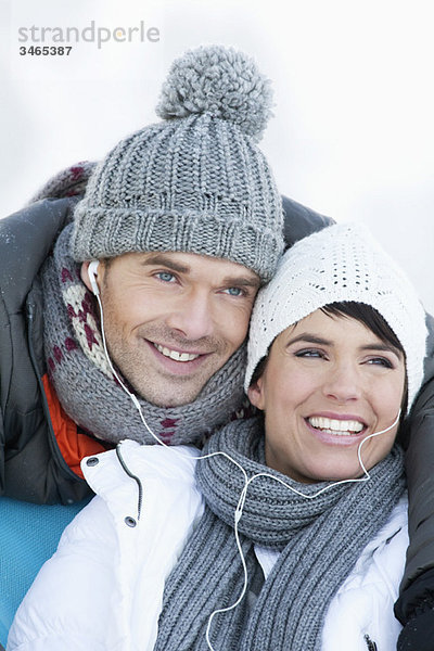 Junges Paar in Winterkleidung  gemeinsam Musik hören