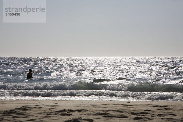 Silhouette eines im Meer stehenden Mannes