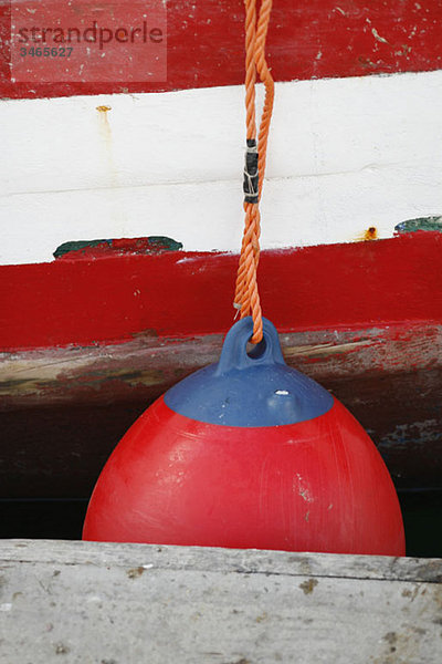 Eine Stoßstange  die an ein Boot gebunden ist  das an einem Steg angedockt ist.