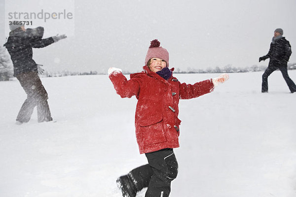 Zwei Eltern und ihre Töchter bei einer Schneeballschlacht