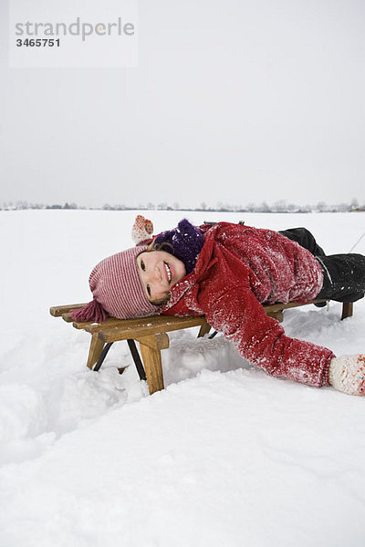 Ein junges Mädchen auf einem Schlitten liegend