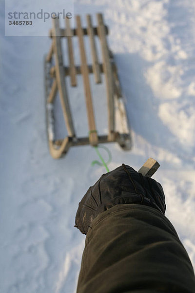 Eine Hand zieht einen Schlitten im Schnee