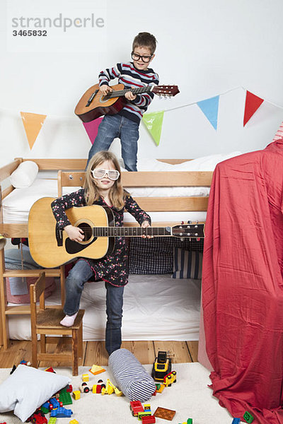 Zwei Kinder spielen mit Gitarren in einem Kinderspielzimmer