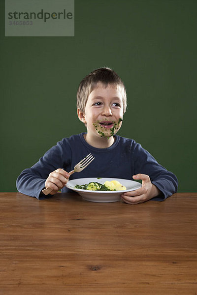 Ein fröhlicher Junge  der sich beim Essen das ganze Gesicht voll frisst.