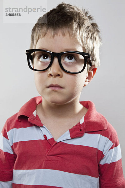 Ein kleiner Junge mit gefälschter Brille schaut nach oben  Studioaufnahme