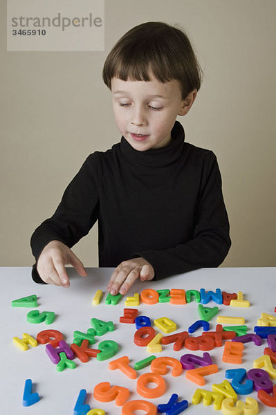 Ein Junge spielt mit Briefmagneten.
