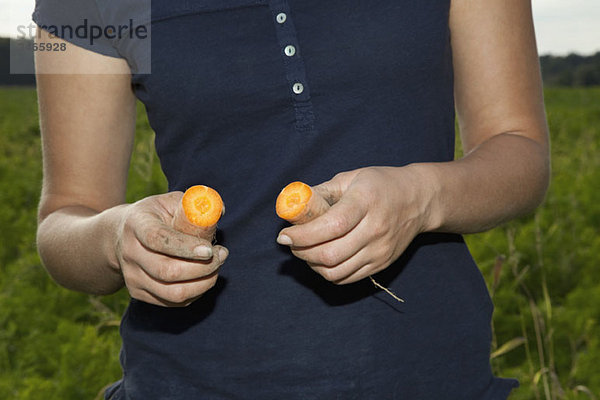 Detail einer Frau mit zwei Karottenhälften