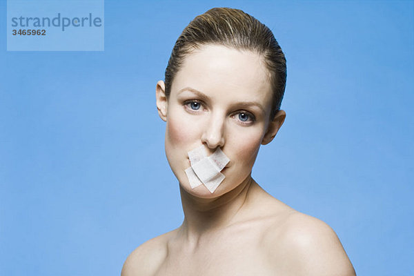 Eine Frau mit Klebeband  das ihren Mund bedeckt.