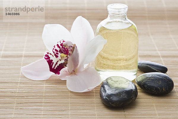 Eine Orchidee  Aromatherapieöl und Lastone Therapiesteine auf einer Tatami-Matte