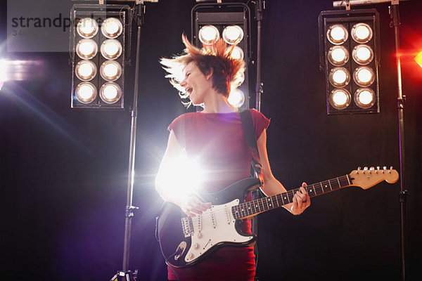 Eine Frau mit E-Gitarre auf der Bühne
