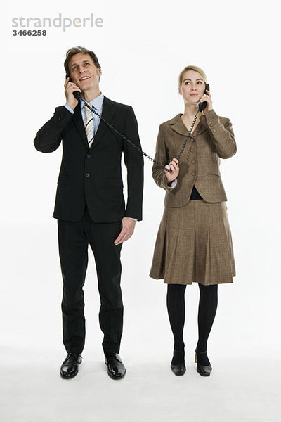 Zwei Geschäftsleute mit Telefonhörern  die mit dem gleichen Kabel verbunden sind.