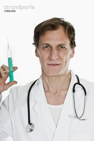 Ein Arzt hält eine Spritze hoch.