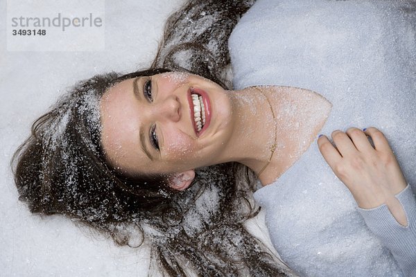 Glückliche junge Frau liegt im Schnee