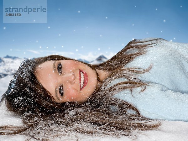 Lächelnde Frau liegt im Schnee-Portrait