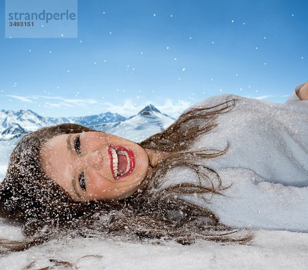 Lachende Frau liegt im gefallenen Schnee