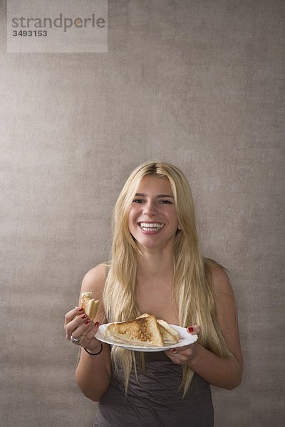 Junge Frau lächelt mit Sandwich