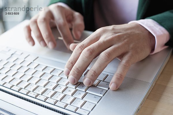 Hände tippen auf dem Laptop