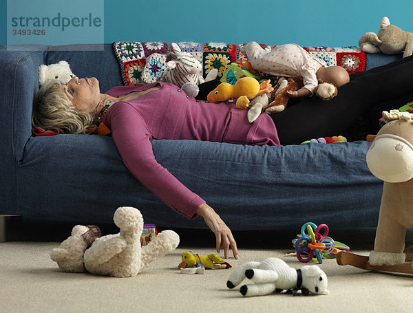 Seniorin schläft auf dem Sofa mit Spielzeug
