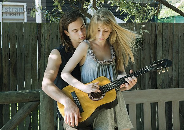 Mädchen spielt Gitarre mit jungem Mann