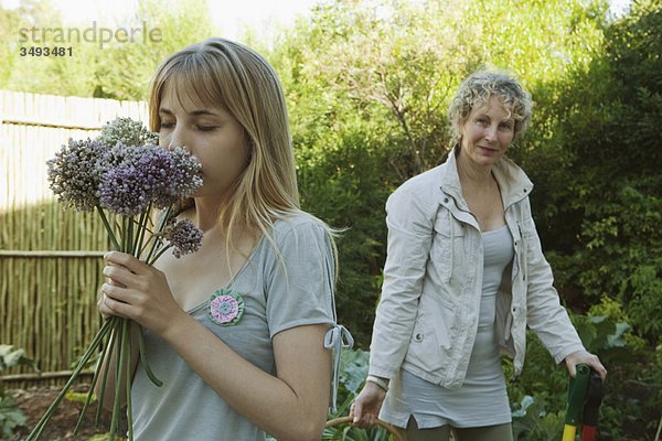 Junge Frau riecht Blumen im Garten