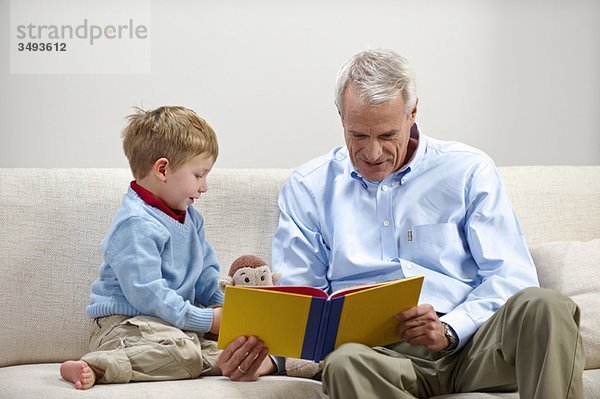 Junge und Großvater lesen Buch