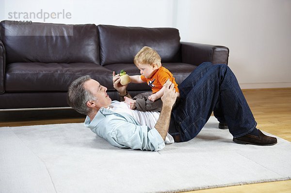 Vater und Baby spielen auf einem Teppich