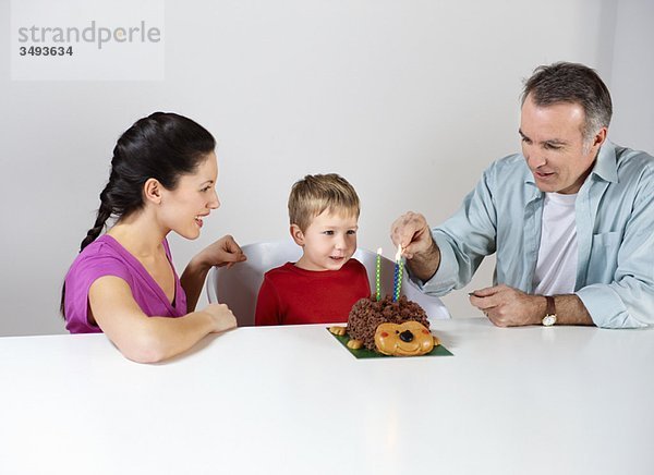 Paar Kerzen auf Kuchen für den Sohn anzünden