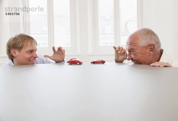 Geschäftsleute  die mit Spielzeugautos spielen