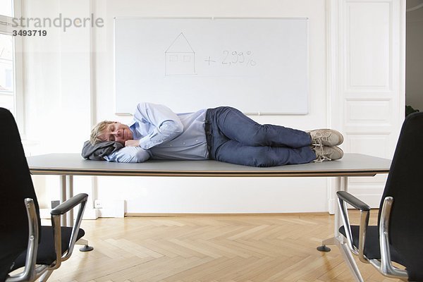 Geschäftsmann schläft auf dem Konferenztisch