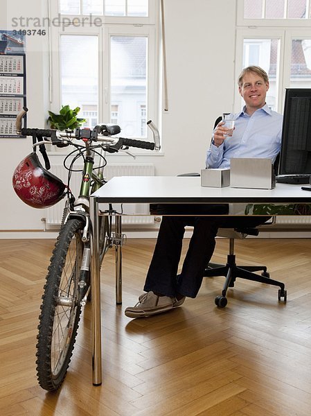 Geschäftsmann im Büro mit Fahrrad