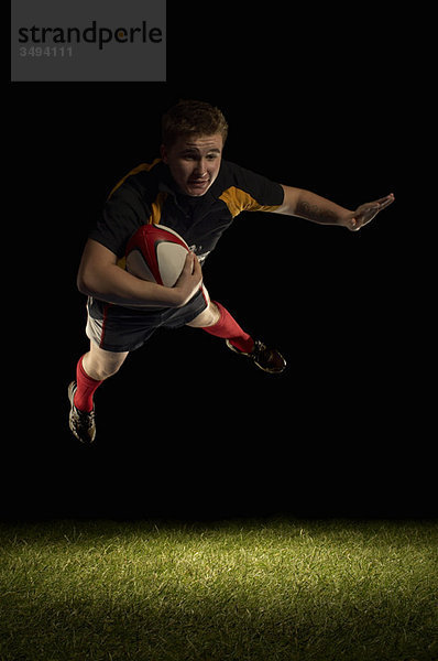 Rugbyspieler in der Luft mit Ball