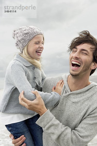 Vater und Tochter lachen am Strand