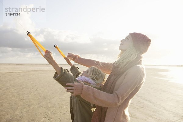 Mutter und Tochter beim Drachenfliegen am Strand