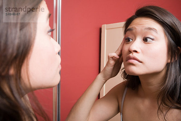 Junge Frau beim Betrachten der Reflexion im Spiegel
