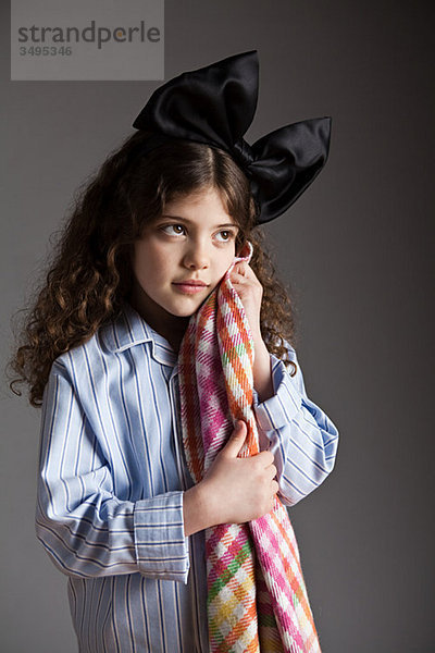 Junges Mädchen gekleidet in Pyjamas mit schwarzen Haaren Bogen  halten Komfort Decke