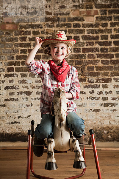 Junges Mädchen verkleidet als Cowgirl mit Schaukelpferd