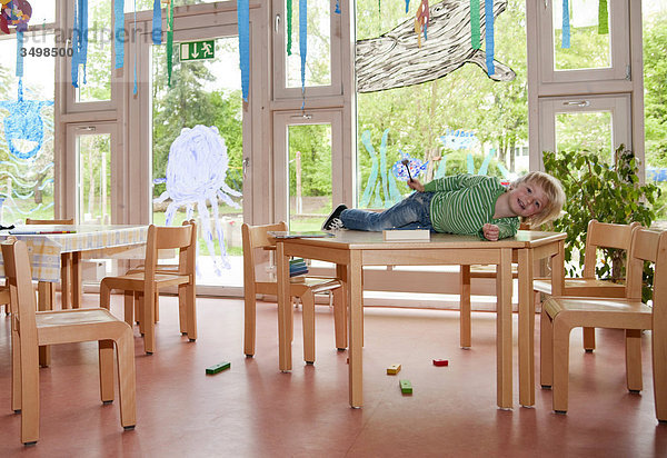 Junge liegt auf einem Tisch im Kindergarten