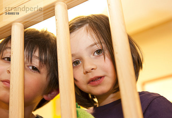 Mädchen und Junge schauen durch ein Geländer  Flachwinkelansicht