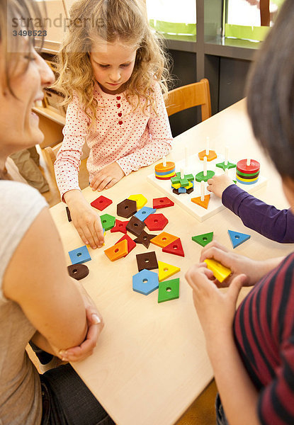 Kindergärtnerin und Kinder spielen auf einem Tisch