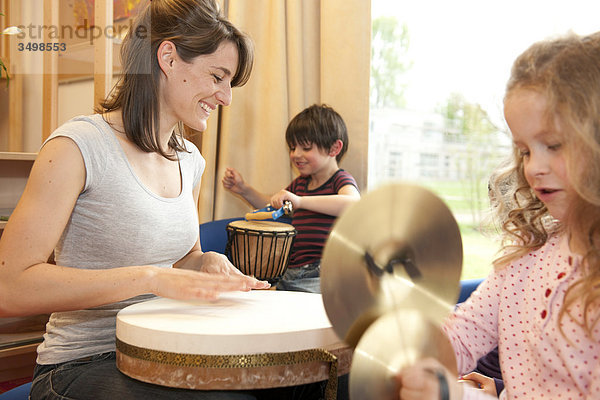 Kindergärtnerin und Kinder musizieren