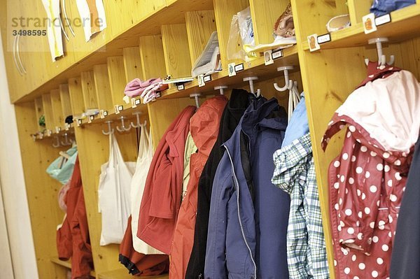 Kleidung in der Garderobe eines Kindergartens hängend