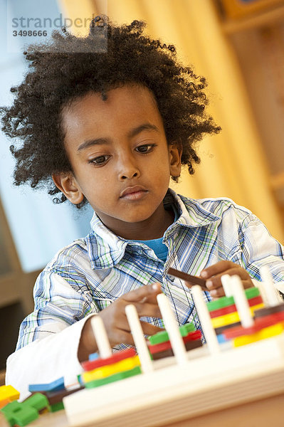 Junge mit Spielzeug an einem Tisch  Porträt