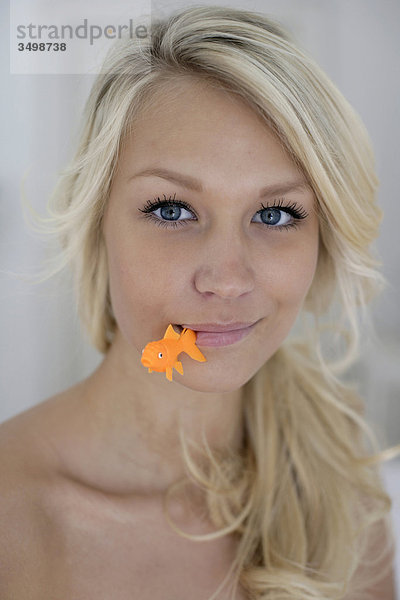 Porträt der jungen Frau Withh Kunststoff Fisch in Mund