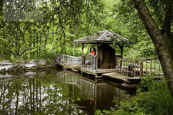 Frau auf einer Holzbrücke an einem Teich im Wald  Erhöhte Ansicht