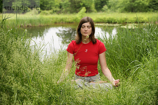 Frau meditiert in der Natur  Frontalansicht