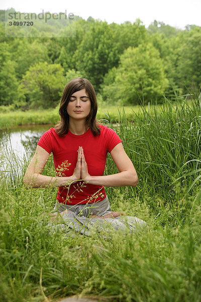 Frau praktiziert Yoga in der Natur  Frontalansicht