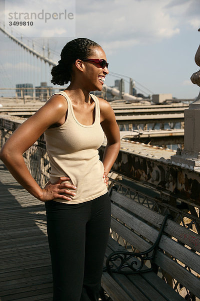 Frau steht auf der Brooklyn Bridge mit den Händen in der Hüfte  New York City  USA