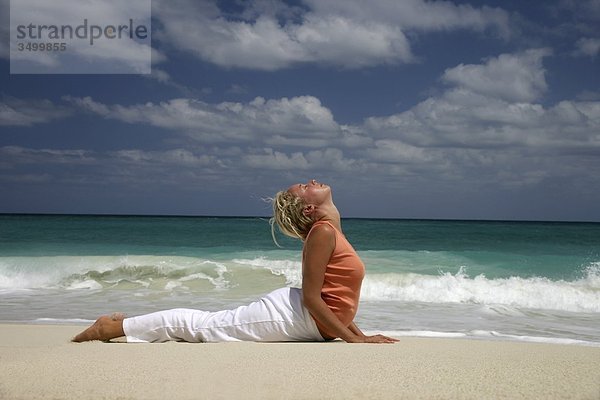 Frau macht Yoga an einem Strand  Seitenansicht