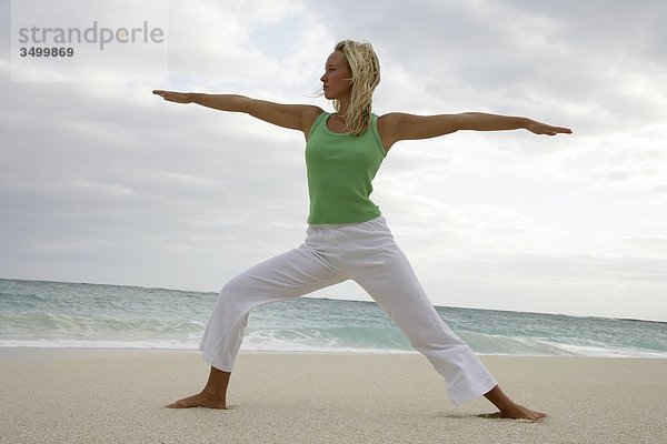 Junge Frau praktiziert Yoga am Strand  Flachwinkelansicht