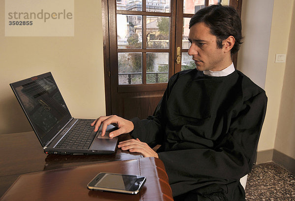 Junger Priester mit laptop